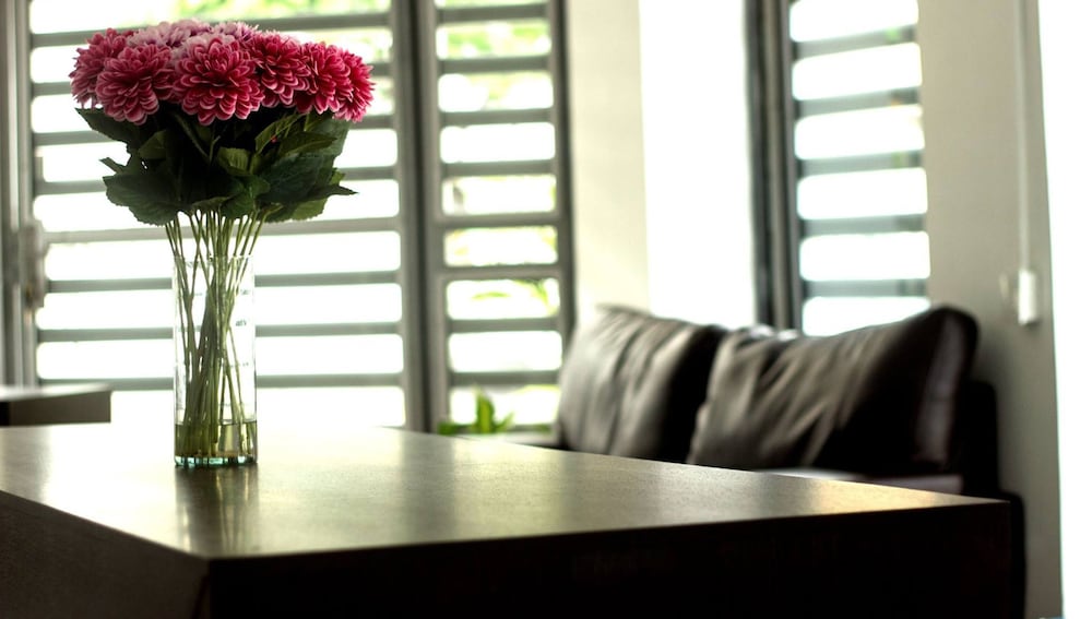 Mesa con flores y sofá en el área común del Apartasuites San Marcos