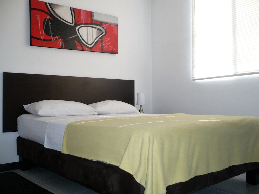 Habitación con cama doble y cabecero oscuro del Apartasuites San Marcos