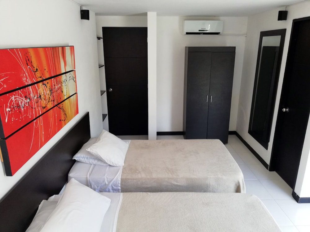 Habitación con dos camas y cuadro rojo del Apartasuites San Marcos