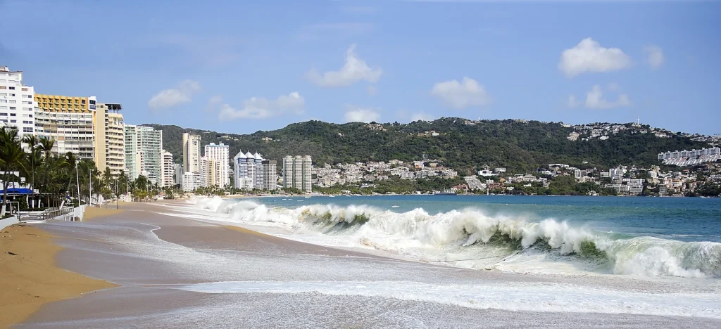 Playa de Acapulco con olas y edificios frente al mar, México