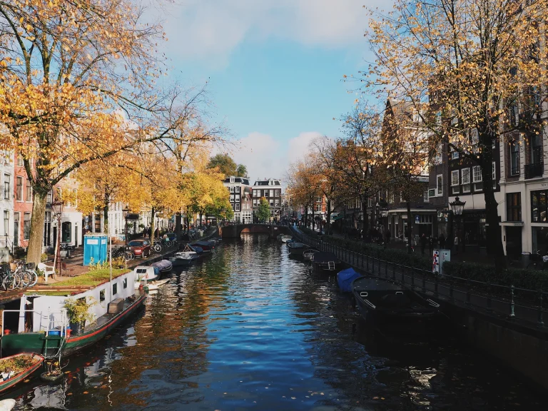 Canal de Ámsterdam con casas tradicionales y árboles en otoño, Países Bajos