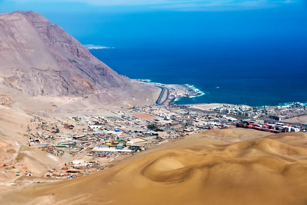 Ciudad costera entre dunas de arena y el océano Pacífico en el norte de Chile