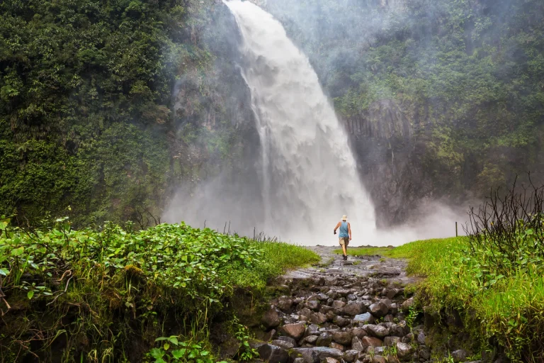 Cascada entre montañas cubiertas de selva, paisaje típico de los alrededores de Baños de Agua Santa, Ecuador