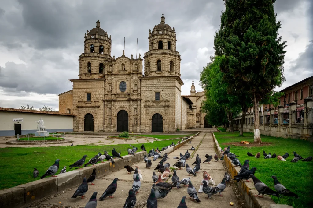 Iglesia colonial de piedra de San Francisco con palomas en la plaza de Cajamarca, Perú