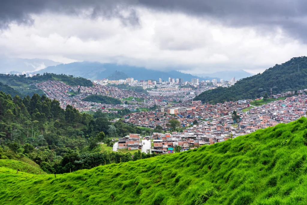 Ciudad colombiana extendida en un valle entre montañas verdes, paisaje andino como el que rodea a Cali, Colombia