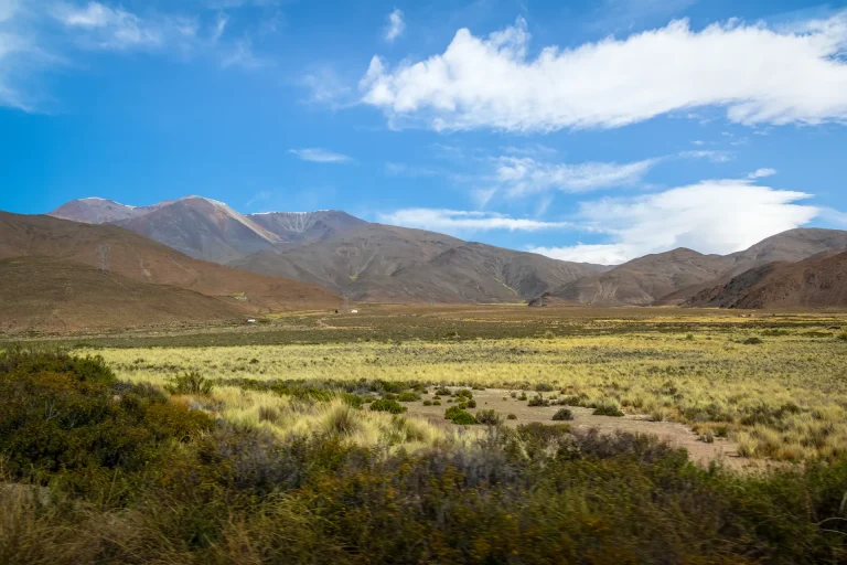 Valle con pastizales y sierras bajo cielo azul en el interior de Argentina, paisaje serrano como el de Córdoba