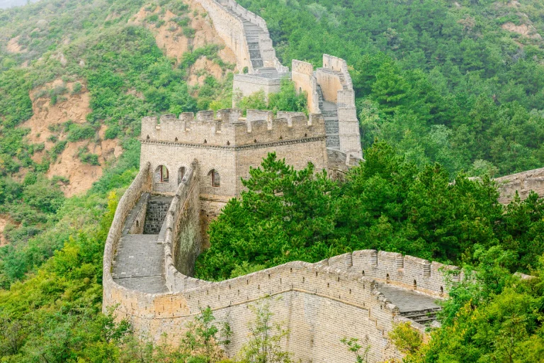 Torres y tramo de la Gran Muralla serpenteando entre montañas verdes, China