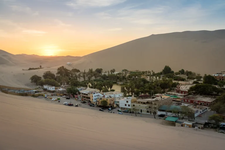 Oasis de Huacachina rodeado de dunas al atardecer, Ica, Perú