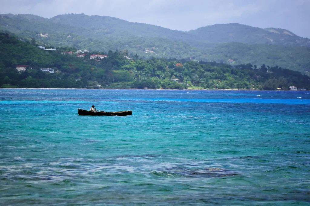 Bote de pescador en el mar turquesa frente a las colinas verdes de Montego Bay, Jamaica
