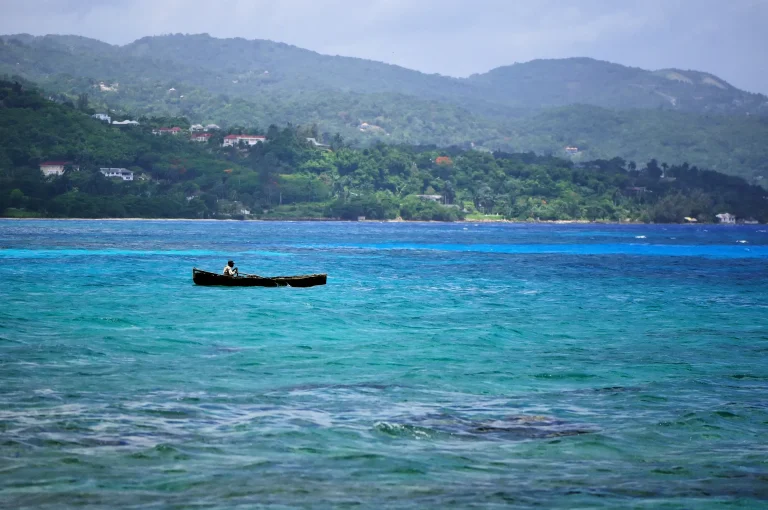Bote de pescador en el mar turquesa frente a las colinas verdes de Montego Bay, Jamaica
