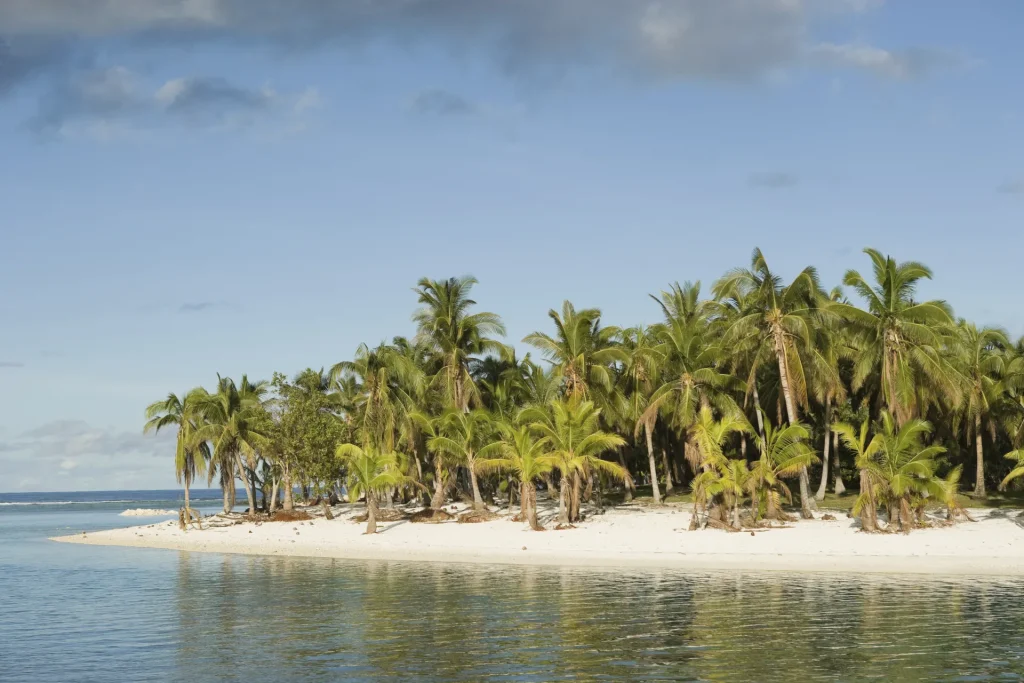 Islote tropical de arena blanca con cocoteros rodeado de mar en calma