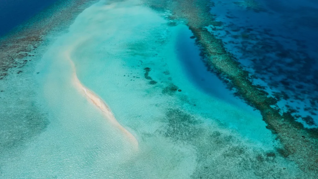 Vista aérea de un banco de arena y arrecife de coral en aguas turquesas