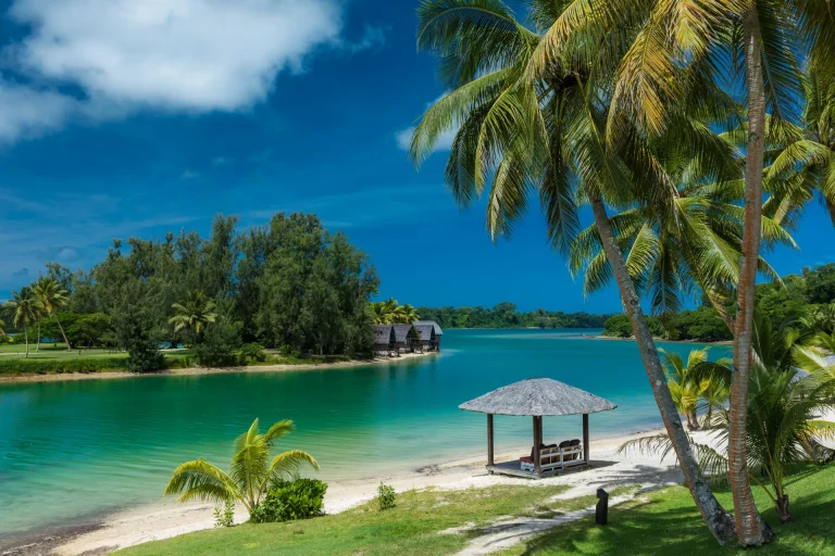 Playa tropical con palmeras y laguna turquesa en la Melanesia