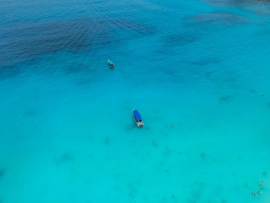Aguas turquesa poco profundas con lancha, como los cayos del Parque Nacional Morrocoy, Venezuela