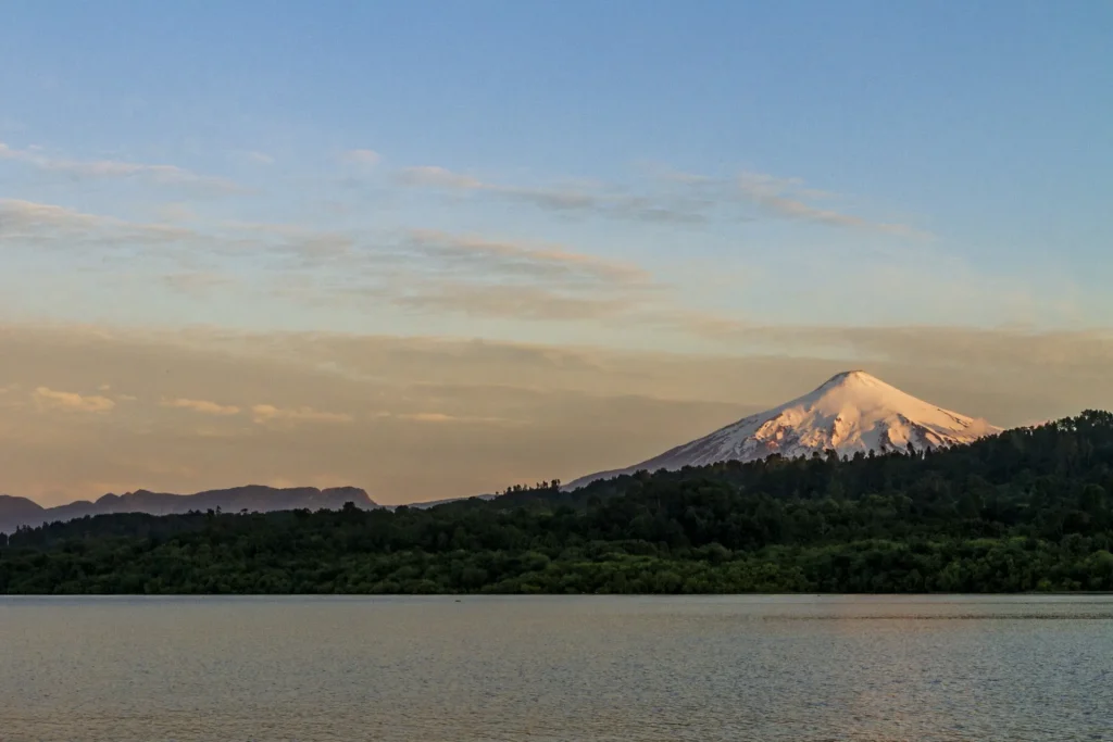 Volcán Villarrica nevado visto desde el lago al amanecer, cerca de Pucón, Chile