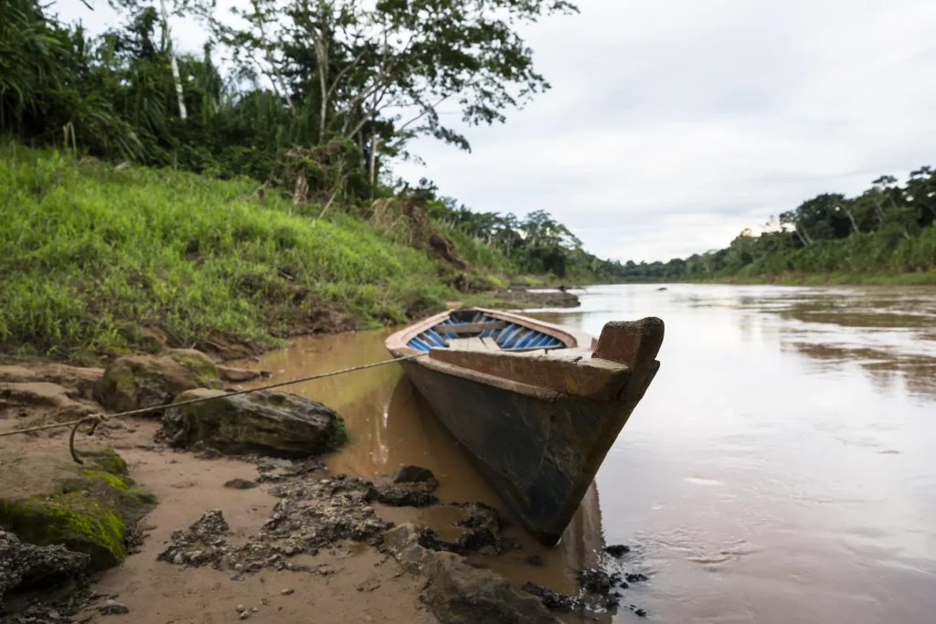 Bote en la orilla de un río amazónico entre selva, paisaje similar al río Beni en Rurrenabaque, Bolivia