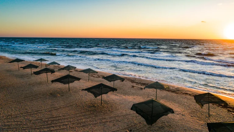Sombrillas en una playa amplia al atardecer, ambiente de balneario como Salinas, Ecuador