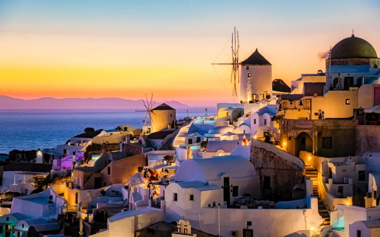 Casas blancas, cúpulas azules y molino de Oia al atardecer, Santorini, Grecia