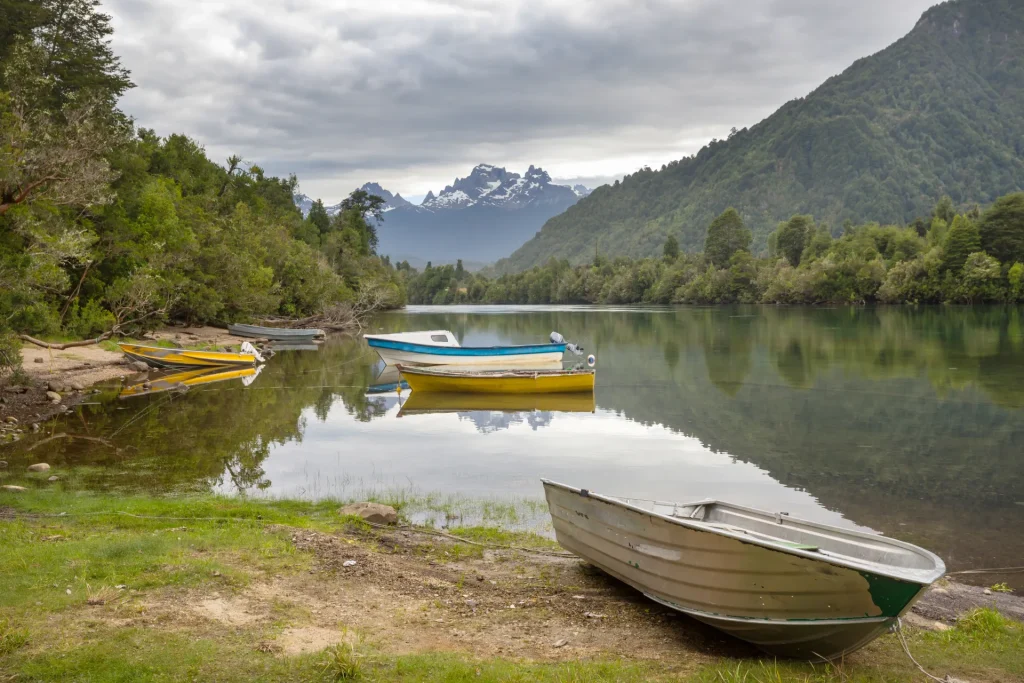 Botes en la orilla de un río rodeado de bosque y montañas en el sur de Chile, región de Valdivia