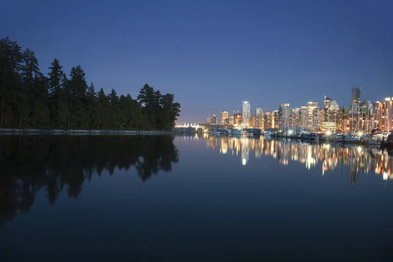 Horizonte iluminado de Vancouver reflejado en el agua visto desde Stanley Park, Canadá