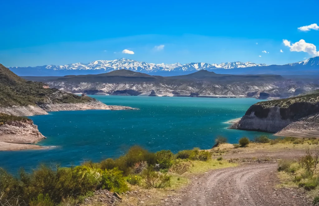 Embalse de aguas turquesa rodeado de sierras, paisaje similar al Lago San Roque de Villa Carlos Paz, Argentina